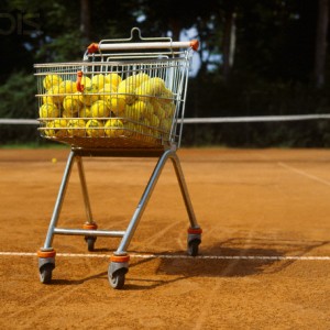 Shopping trolley with yellow tennis balls on tennis court